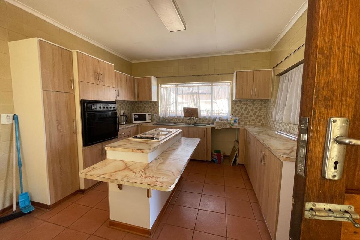 A functional kitchen featuring wood-look cabinetry, a central island with a hob, built-in oven, and tiled flooring throughout.
