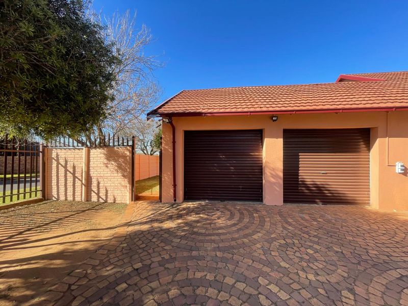Exterior view of a double garage featuring roller doors, a paved driveway, and secure perimeter walling.