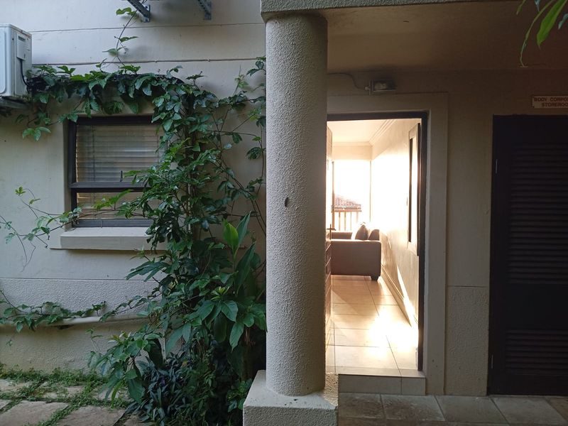 A view of the rear exterior area featuring a concrete column, tiled flooring, and access to an interior space through a doorway.