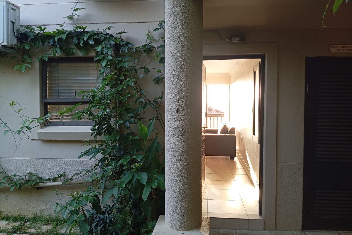 A view of the rear exterior area featuring a concrete column, tiled flooring, and access to an interior space through a doorway.