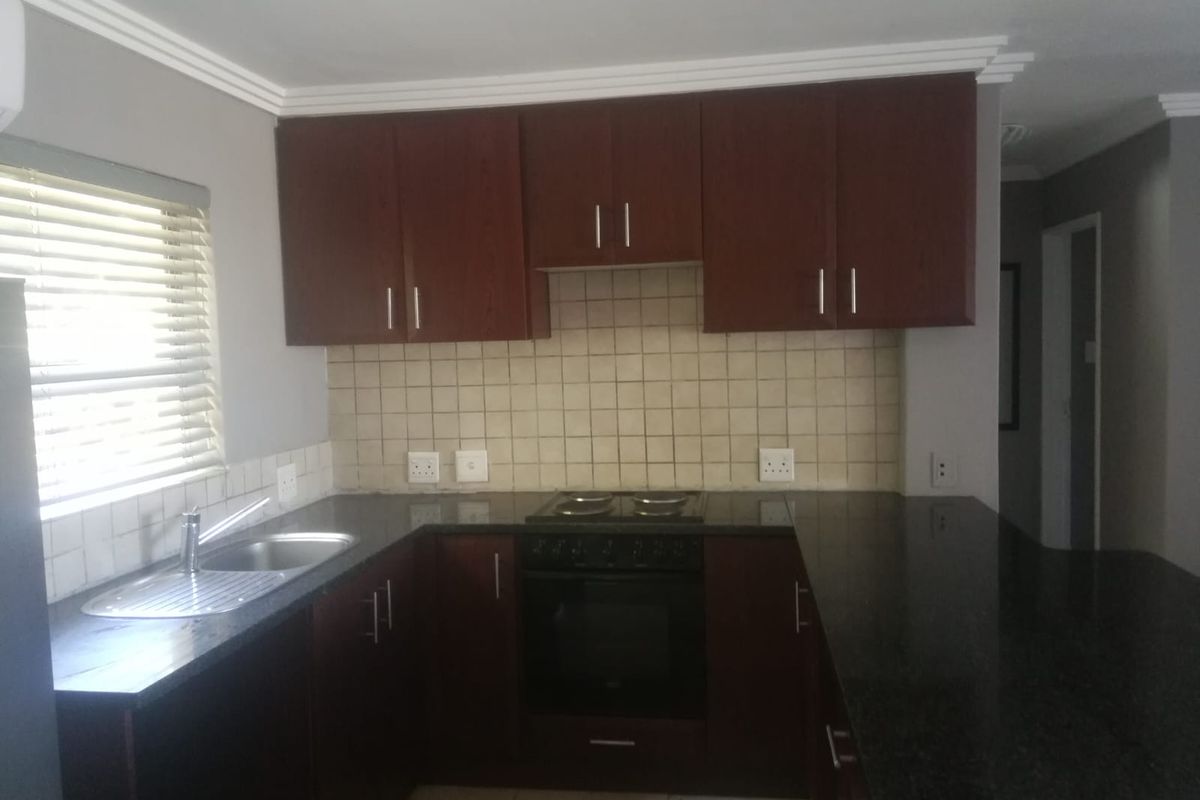 A functional kitchen featuring dark wood cabinetry, granite countertops, a built-in oven with hob, and a tiled backsplash.