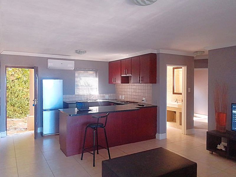 Open-plan living area featuring a kitchen with dark wood cabinetry, granite countertops, tiled backsplash, and direct access to an outdoor patio area.
