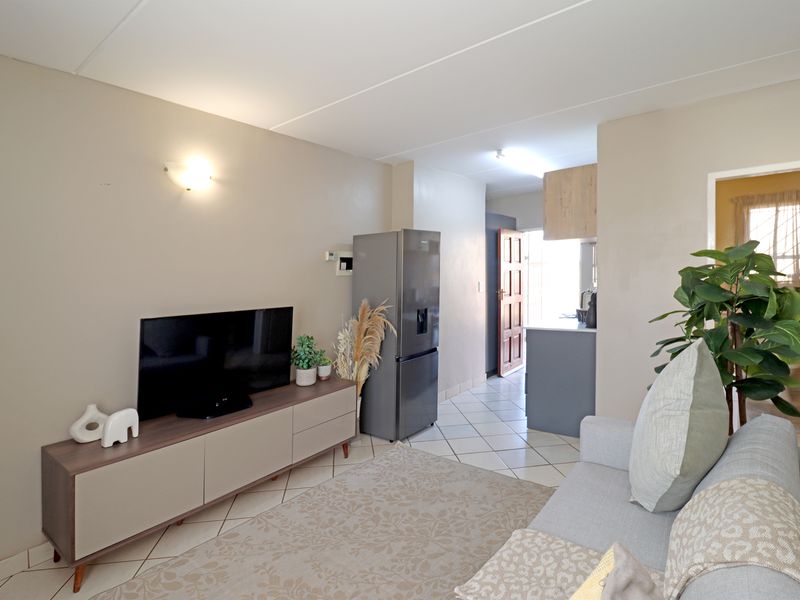 Open-plan living area featuring tiled flooring and a seamless transition into the kitchen space, providing a functional and connected layout.