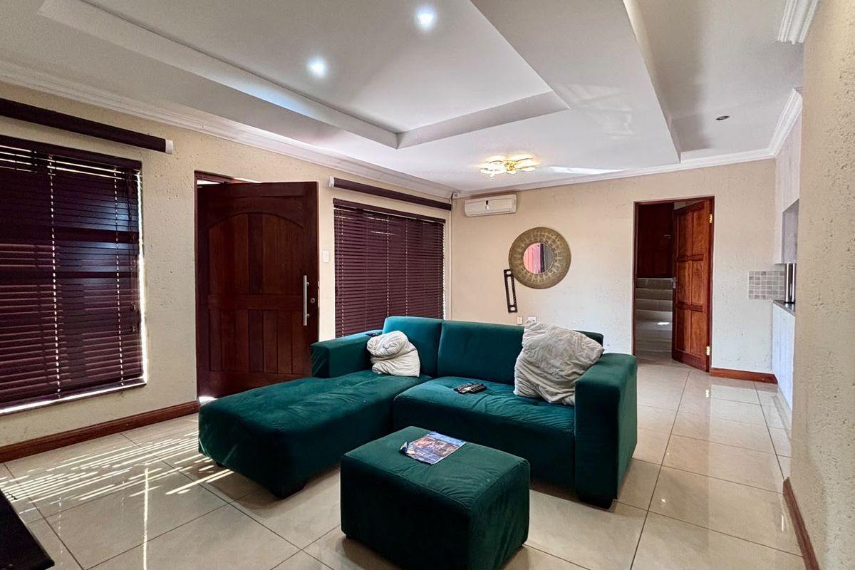 Spacious living room featuring tiled flooring, recessed ceiling with downlights, and an integrated air conditioning unit.