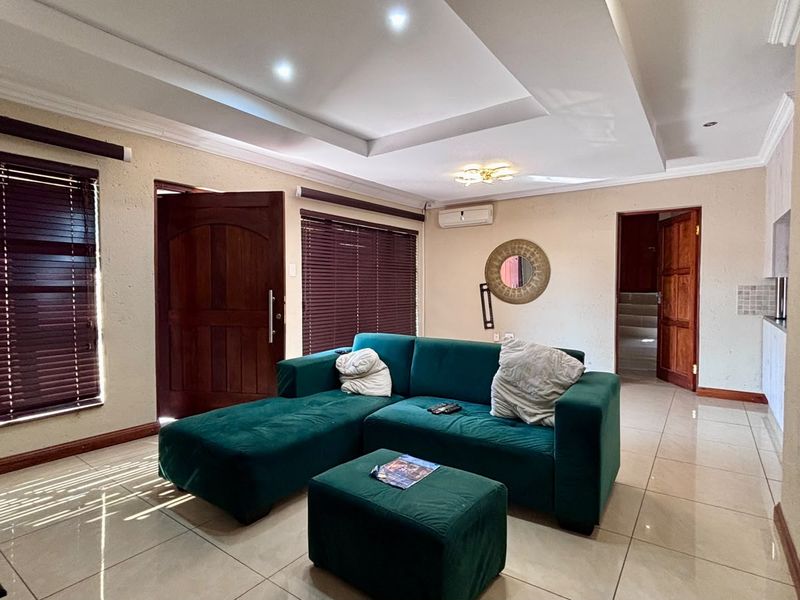 Spacious living room featuring tiled flooring, recessed ceiling with downlights, and an integrated air conditioning unit.