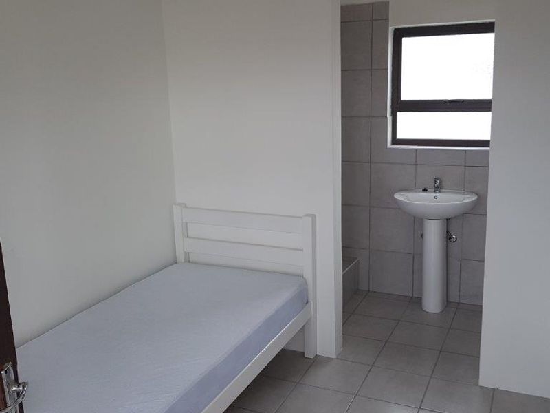 A compact bedroom featuring tiled flooring and an integrated pedestal basin area.