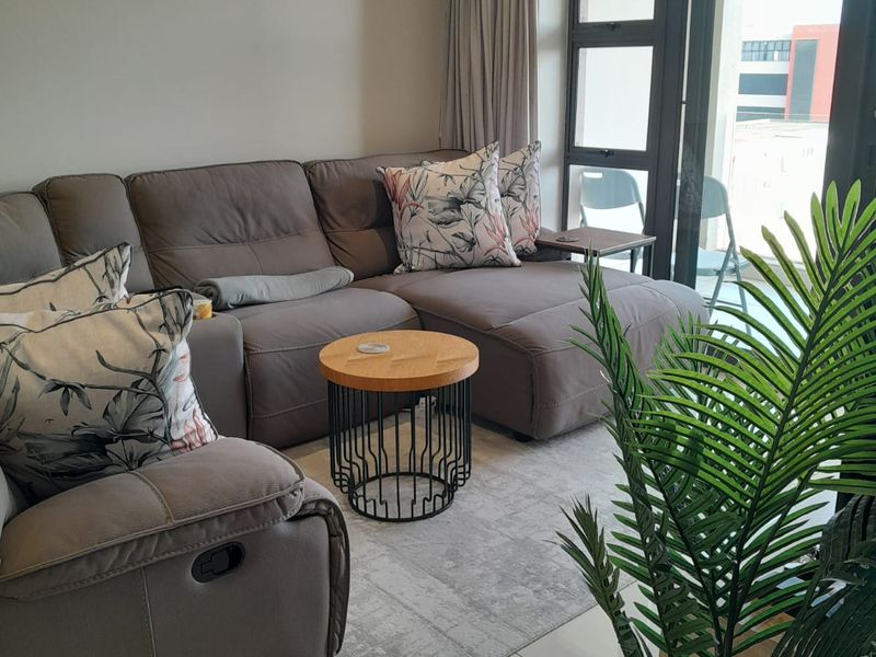 A well-maintained living room featuring tiled floors and a large sliding glass door providing access to an outdoor balcony area.