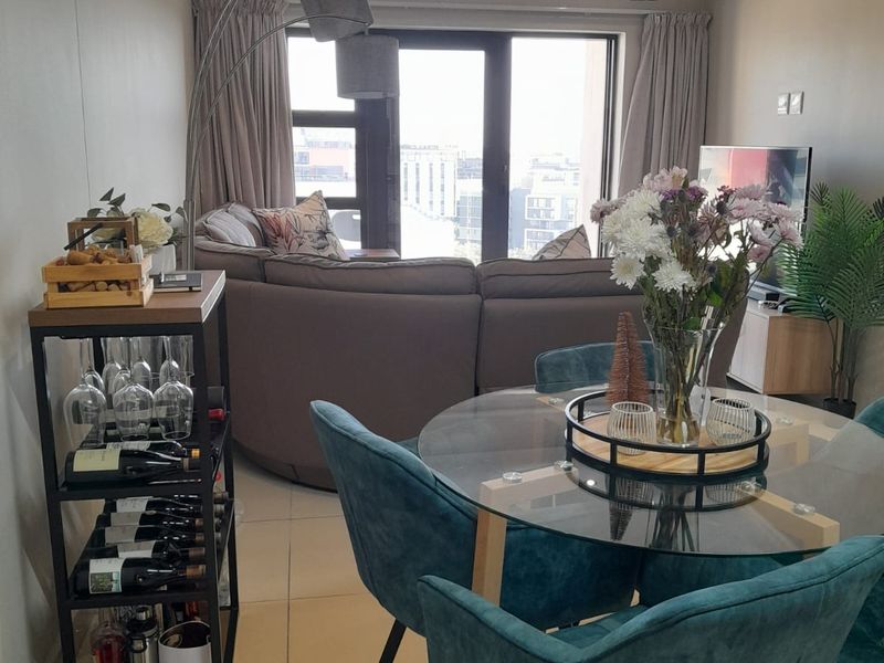 An open-plan living and dining area featuring tiled flooring, recessed downlighting, and a large sliding glass door providing access to a balcony.