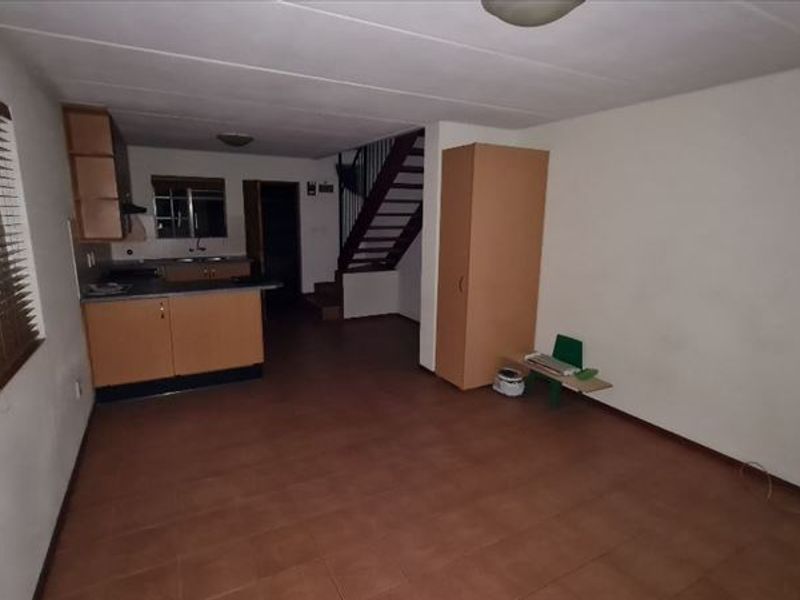 Open-plan living area featuring a kitchen with built-in cabinetry and a staircase leading to the upper level.