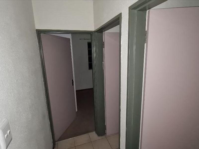 A functional hallway connecting multiple rooms, featuring tiled flooring and neutral painted doors with matching frames.