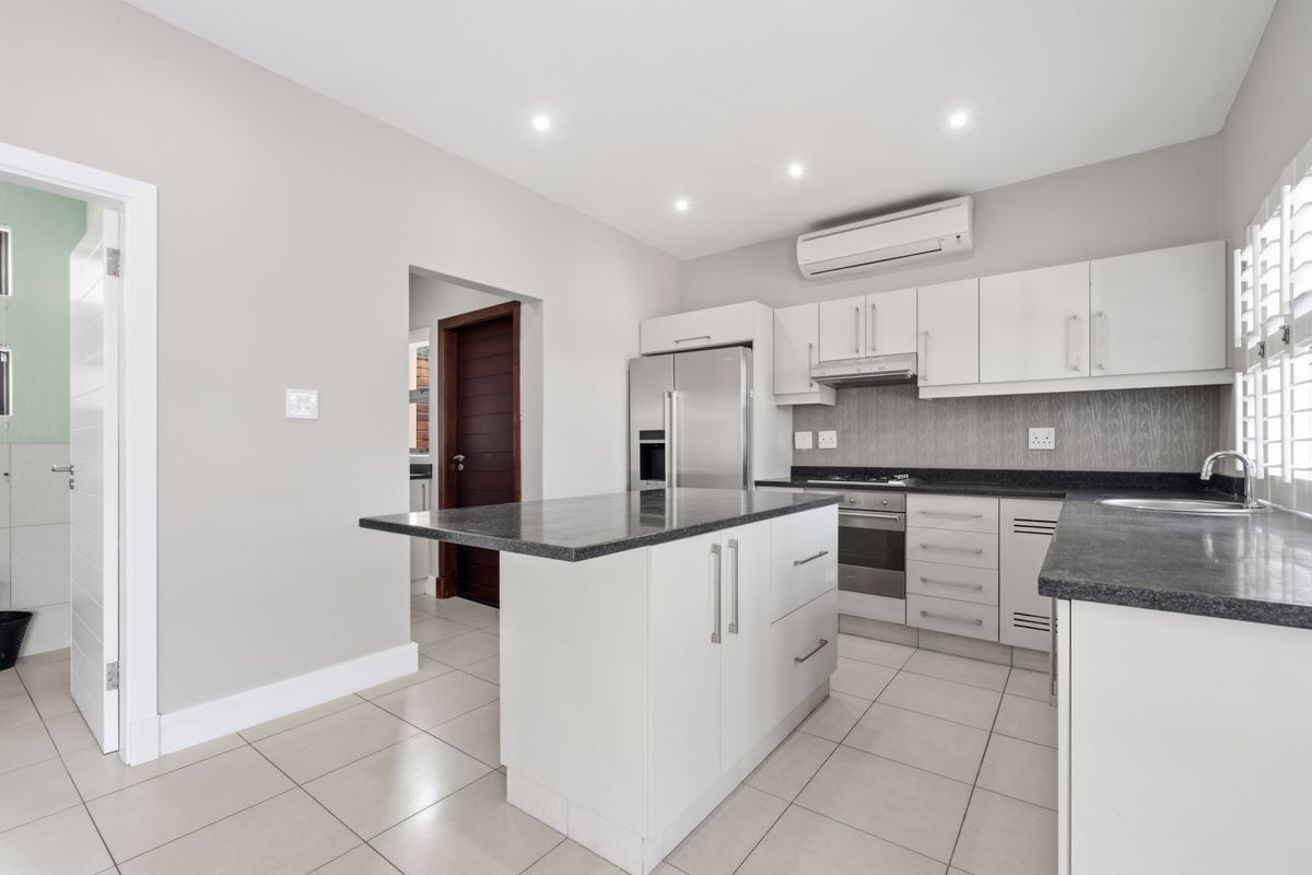 Modern kitchen featuring white cabinetry, granite countertops, a central island, built-in appliances, and tiled flooring with recessed lighting.