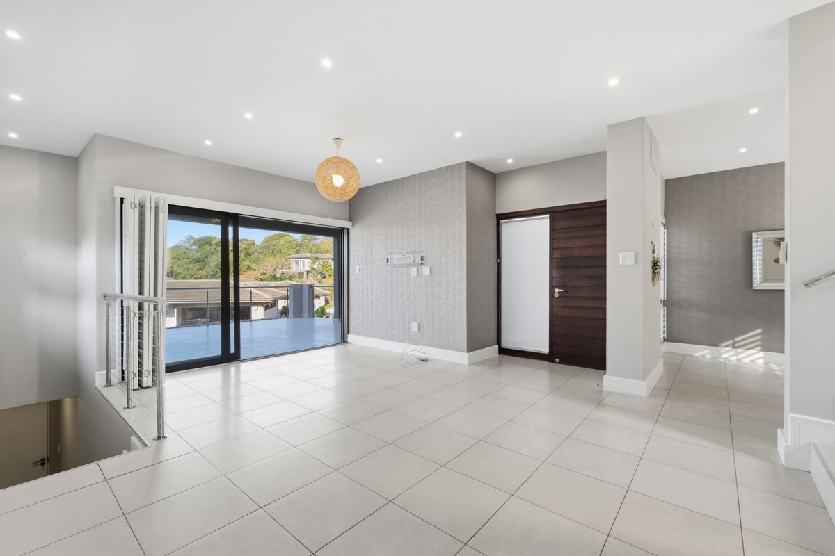 Spacious, light-filled living area featuring neutral tiled flooring, modern recessed lighting, and large sliding doors opening onto an outdoor balcony.