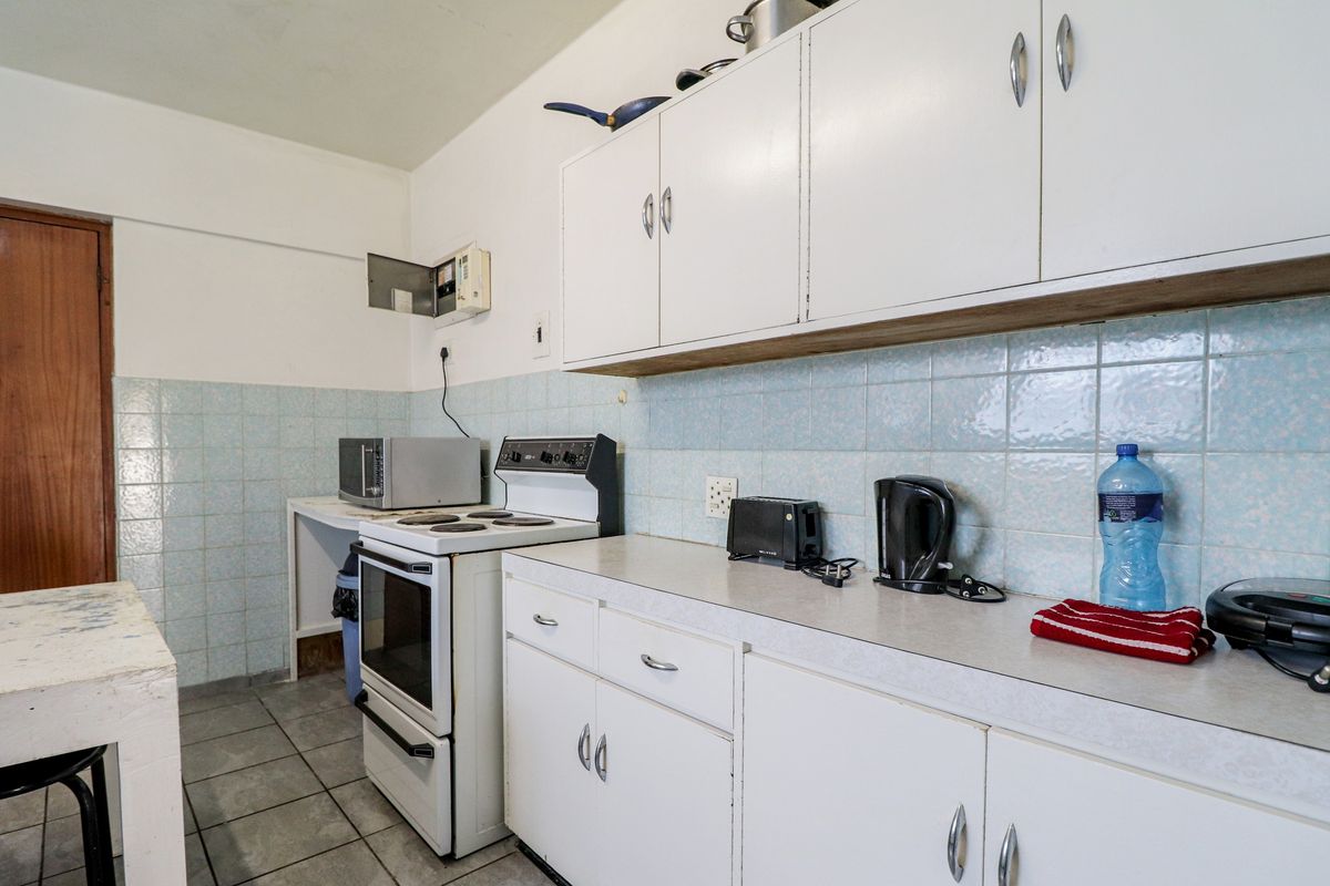 A dated kitchen featuring original cabinetry, tiled backsplash, and a freestanding stove, offering significant potential for modernization and renovation.
