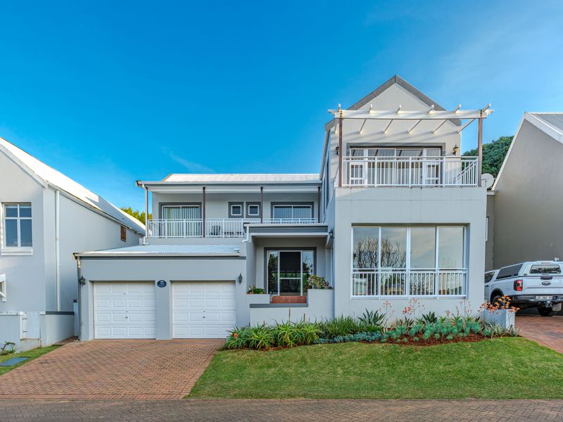 A well-maintained double-story residential property featuring a double garage, paved driveway, and upper-level balconies with a pergola.