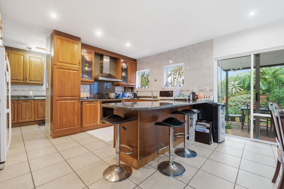 Spacious kitchen featuring wooden cabinetry, granite countertops, built-in appliances, and direct access to the outdoor patio area through sliding glass doors.