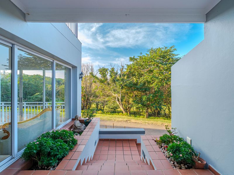 A covered outdoor staircase with tiled steps and built-in planters, leading to a bright, open-plan living area through large sliding glass doors.