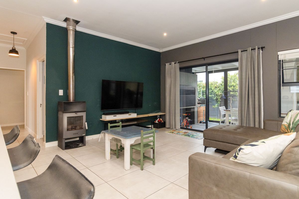 Spacious living room featuring a modern freestanding fireplace, tiled flooring, and large sliding glass doors providing seamless access to the outdoor patio area.