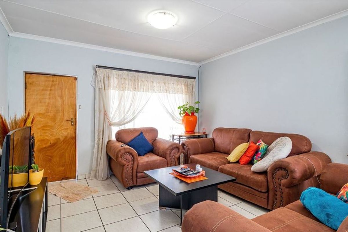 A living room featuring tiled flooring and a wood-burning stove flue, offering a functional space with potential for cosmetic updates.