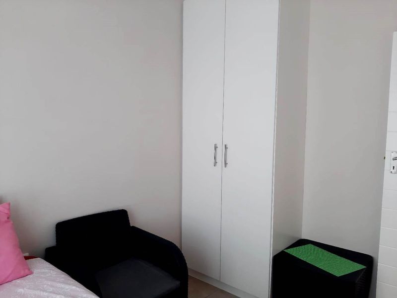 A bedroom featuring a clean, white built-in wardrobe with modern handles, providing efficient storage space.