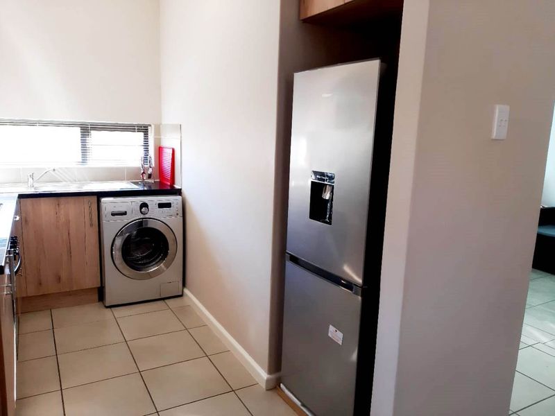 A functional laundry area featuring built-in cabinetry, a stainless steel sink, and tiled flooring, providing a dedicated space for utility and washing tasks.