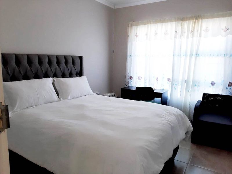 A bedroom featuring tiled flooring and neutral wall finishes, providing a functional space with natural light from the window.