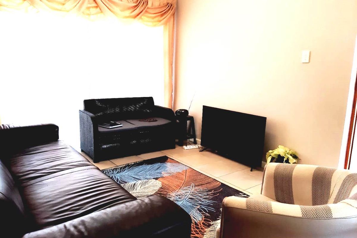 A living room area featuring tiled flooring and a large sliding glass door with window treatments.