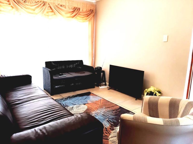 A living room area featuring tiled flooring and a large sliding glass door with window treatments.