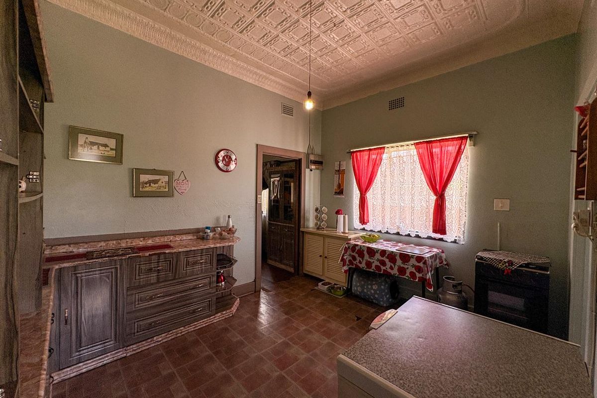 A vintage-style kitchen featuring a decorative pressed metal ceiling, built-in cabinetry, and tiled flooring, offering potential for a modern renovation.