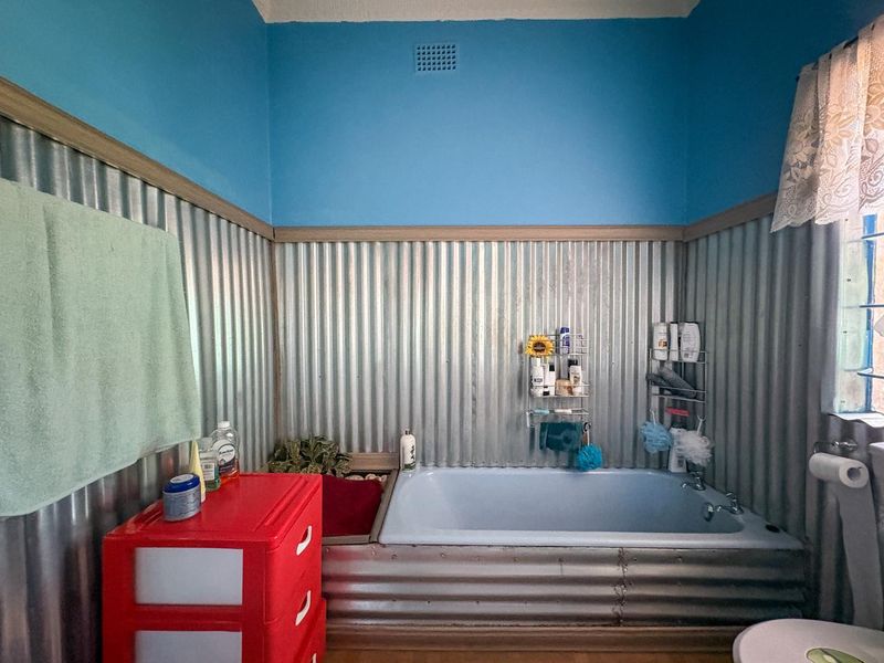 Bathroom featuring a built-in bathtub with unique corrugated metal wall cladding and a blue painted upper wall section.