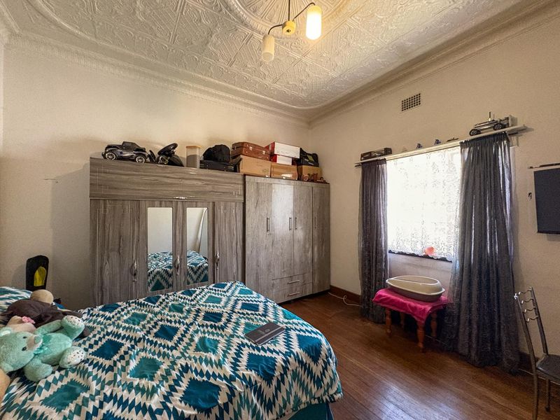 A bedroom featuring original ornate pressed metal ceilings, a ceiling rose, and timber flooring, offering a classic architectural foundation.