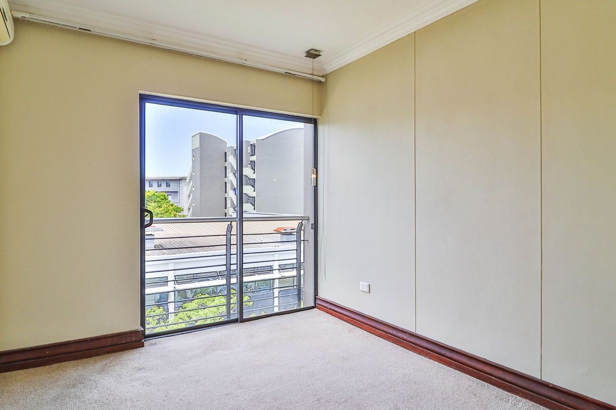 An empty bedroom featuring carpet flooring, coving, and a sliding glass door providing access to a balcony.