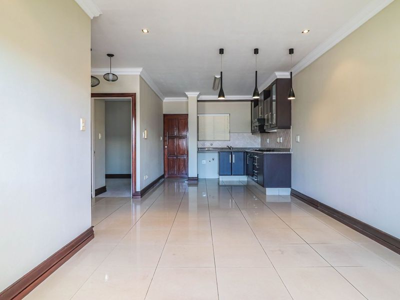 Spacious open-plan living area featuring tiled floors, crown molding, and a modern kitchen with built-in cabinetry, granite countertops, and integrated appliances.
