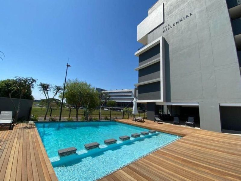 Modern apartment complex featuring a well-maintained swimming pool with timber decking and contemporary architectural design.