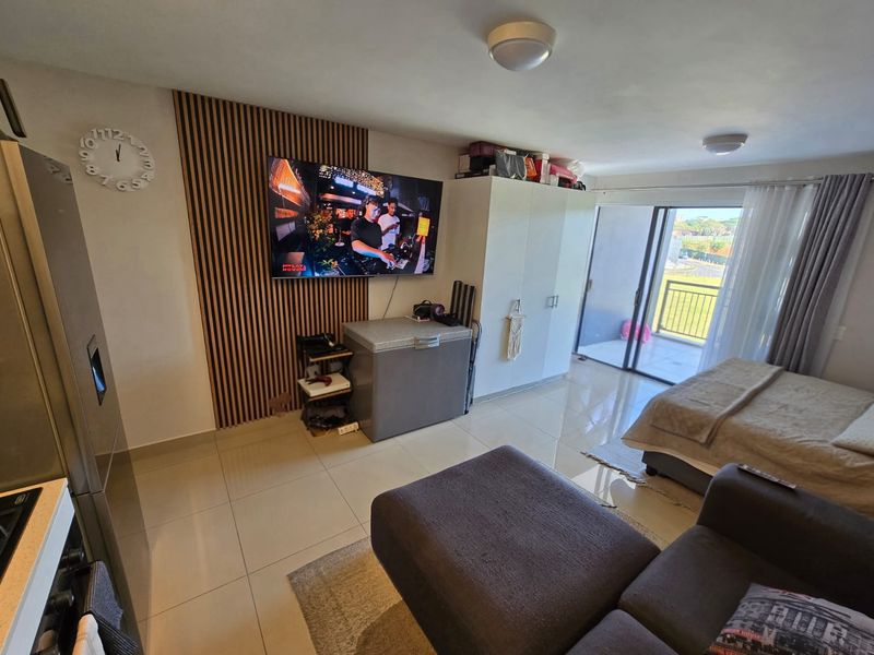 Open plan living area featuring modern slatted timber wall paneling, tiled flooring, and direct access to a private balcony through sliding glass doors.