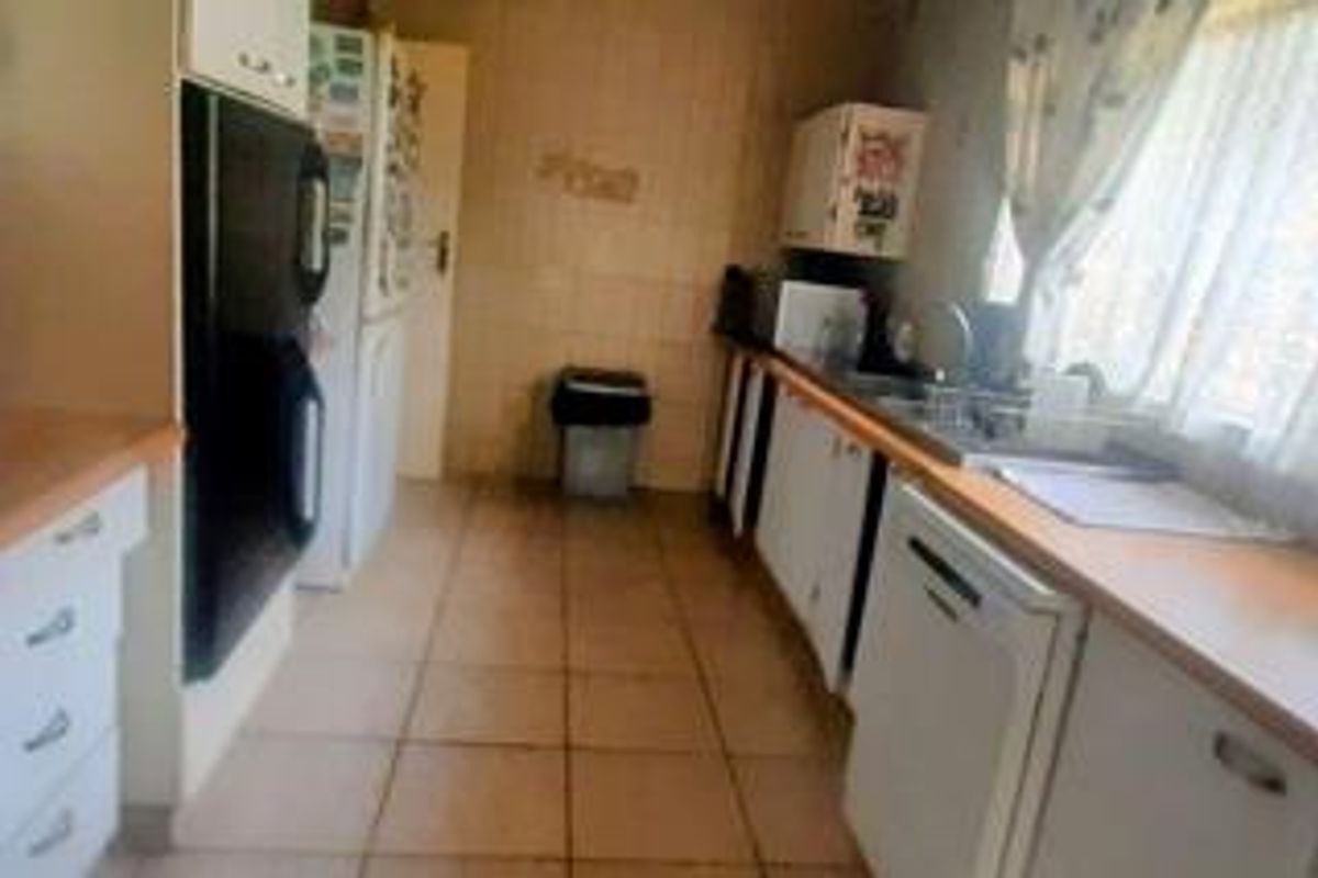 A functional kitchen featuring tiled flooring, built-in cabinetry, and laminate countertops, offering a practical layout that could benefit from modern cosmetic updates.