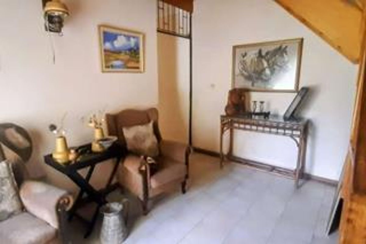 A living area featuring tiled flooring and a staircase structure, offering a functional space with potential for modern updates.