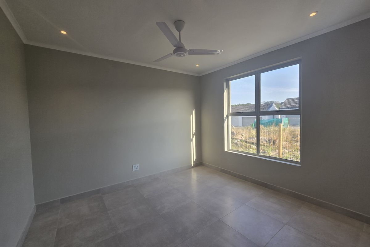 A bright, modern, and empty bedroom featuring neutral grey tiled flooring, recessed downlights, and a ceiling fan, ready for personalization.