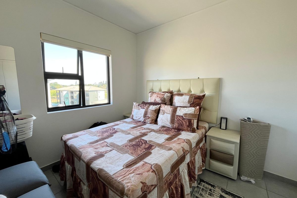 A functional bedroom featuring tiled flooring, a large window with a roller blind, and neutral wall finishes.