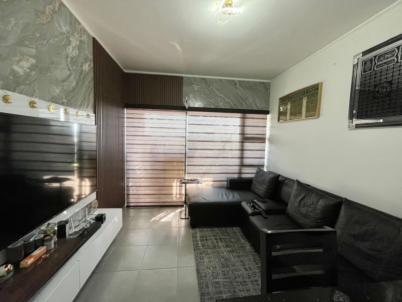 A modern living room featuring tiled flooring, decorative slatted wood wall paneling, and marble-effect wall accents with integrated roller blinds.