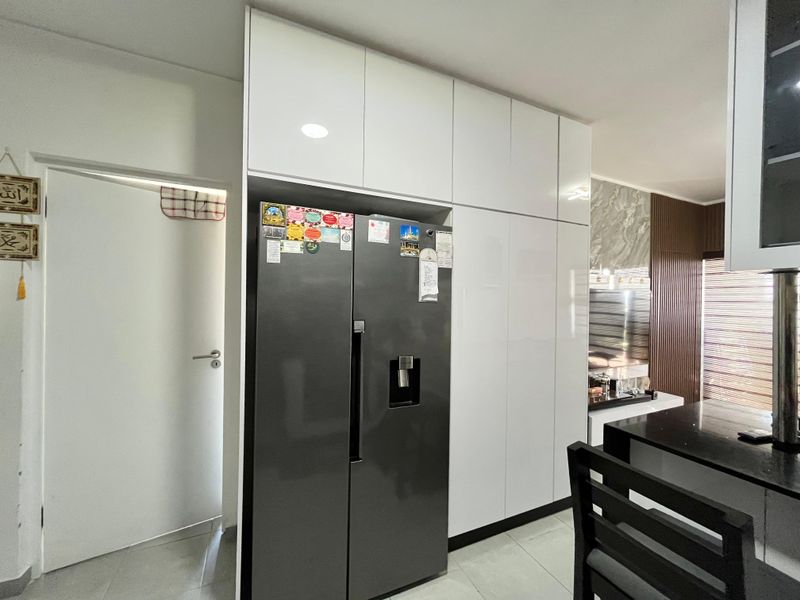 Modern kitchen featuring sleek white floor-to-ceiling cabinetry, integrated refrigerator housing, and a dark stone countertop, offering a clean and contemporary aesthetic.