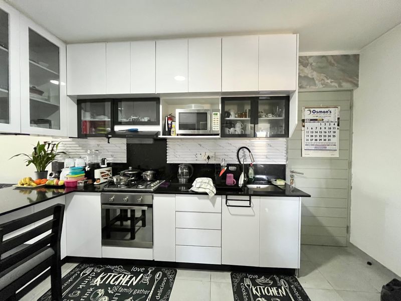 A modern kitchen featuring white cabinetry, black granite countertops, a built-in gas hob, oven, and integrated microwave with a tiled backsplash.