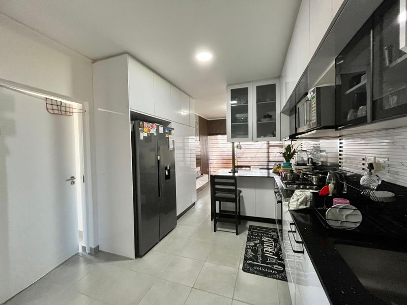 Modern kitchen featuring sleek white cabinetry, black granite countertops, integrated appliances, and tiled flooring, offering a functional and contemporary cooking space.