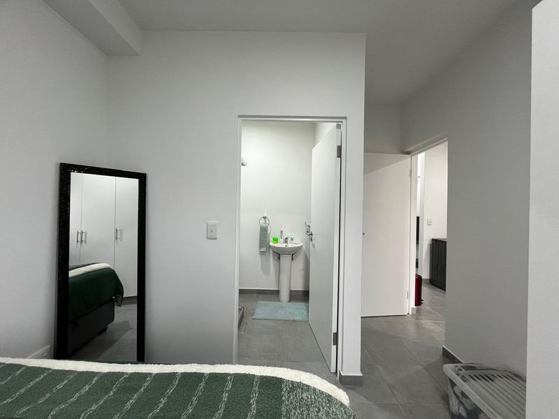 Bedroom featuring tiled flooring, built-in wardrobe, and an en-suite bathroom with a pedestal sink.