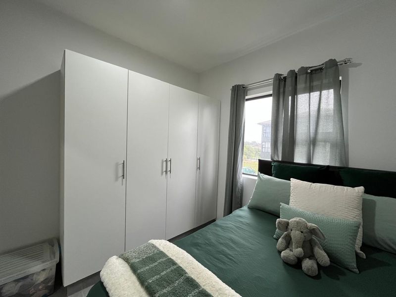 A well-maintained bedroom featuring a large, modern white built-in wardrobe and neutral wall finishes.