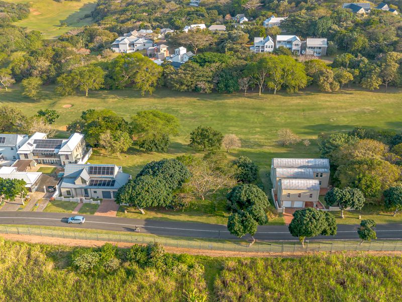 An aerial view of a residential estate featuring multiple homes, solar installations, and surrounding green space adjacent to a golf course.