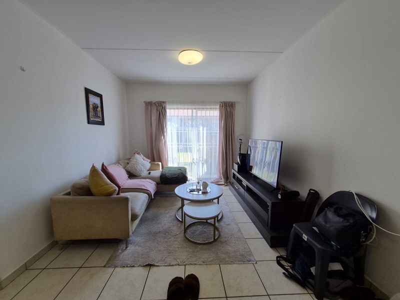 A functional living room featuring tiled flooring and a sliding glass door that provides access to the exterior.