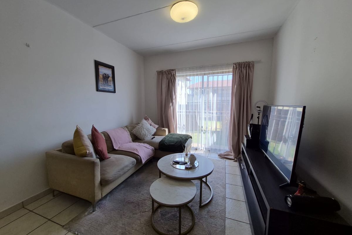 A functional living room featuring tiled flooring and a sliding glass door providing natural light and access to the exterior.
