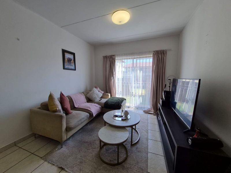 A functional living room featuring tiled flooring and a sliding glass door providing natural light and access to the exterior.