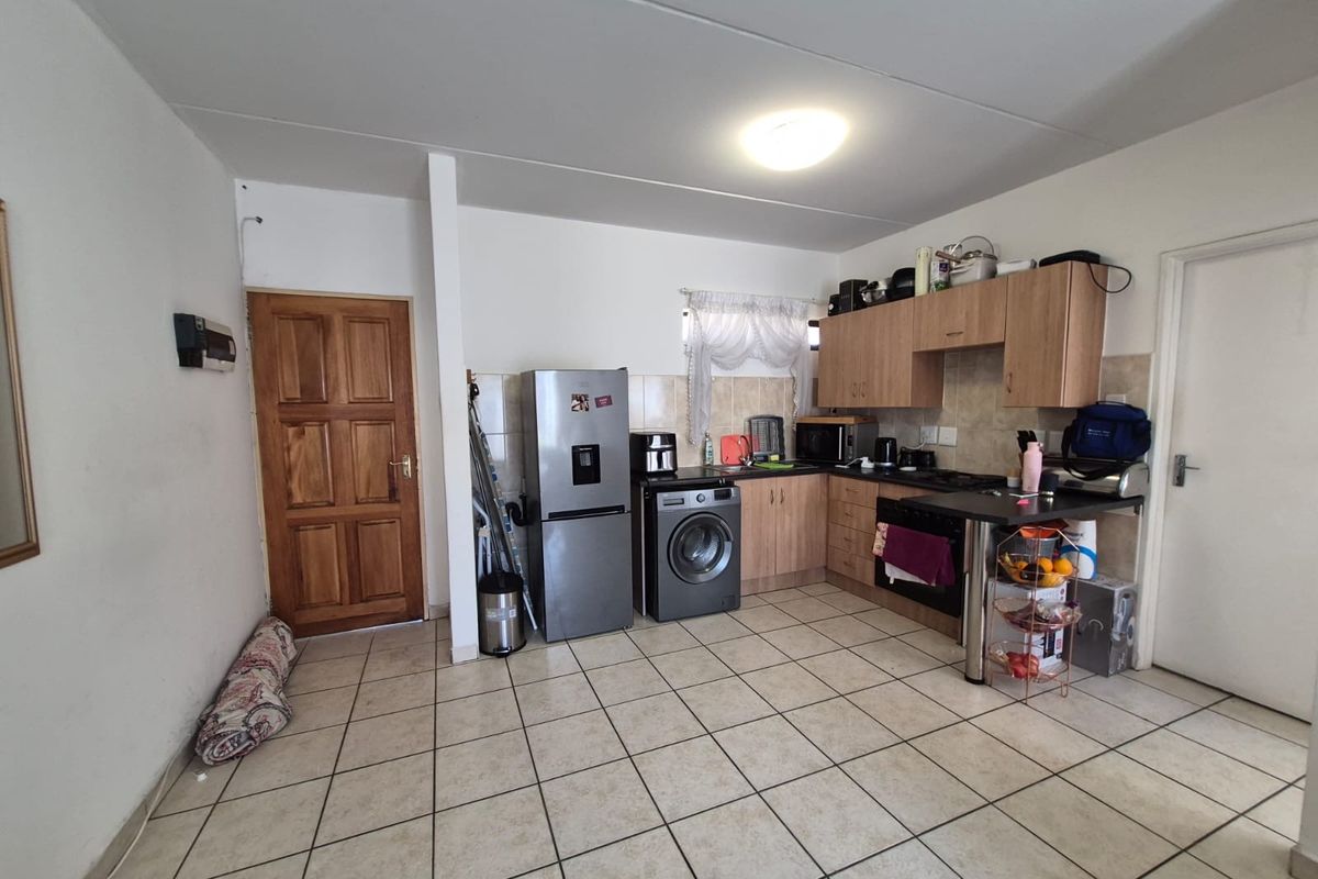 Functional kitchen featuring tiled flooring, built-in cabinetry, a breakfast counter, and integrated cooking appliances.