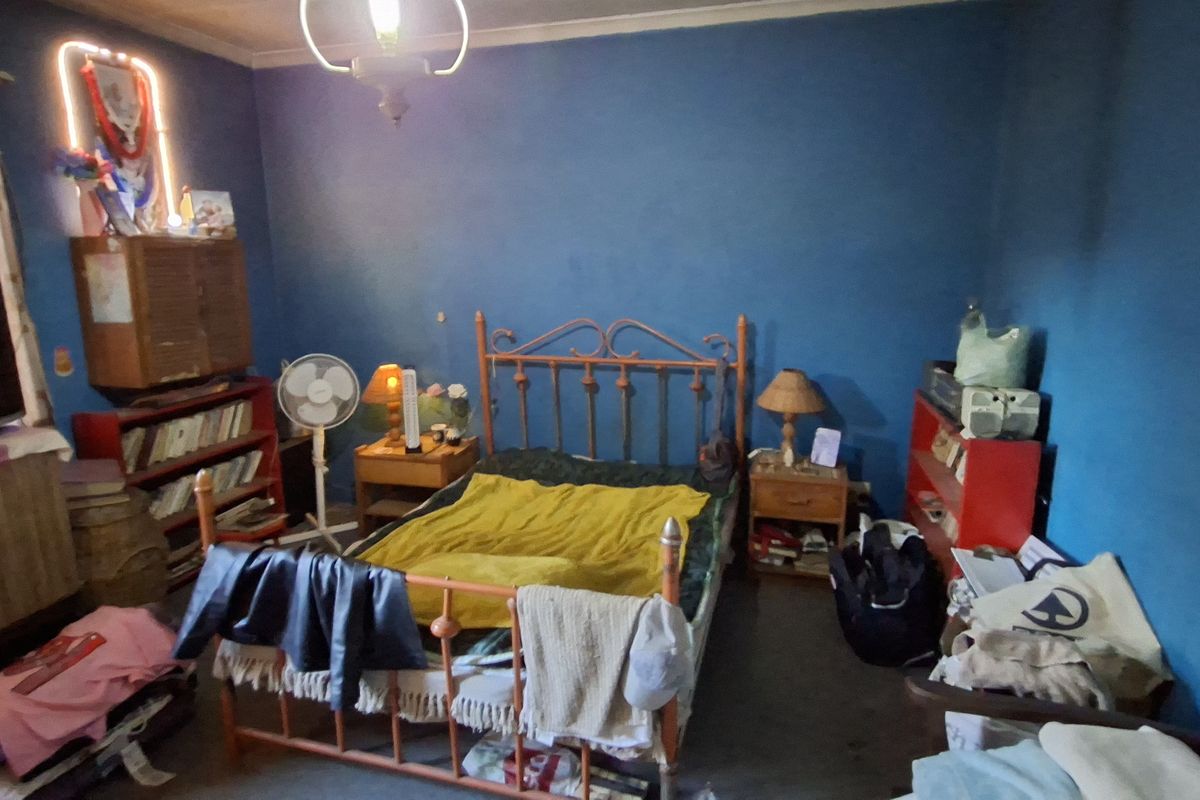 A bedroom featuring blue painted walls and a metal bed frame, requiring cosmetic updates to improve the overall aesthetic and condition.